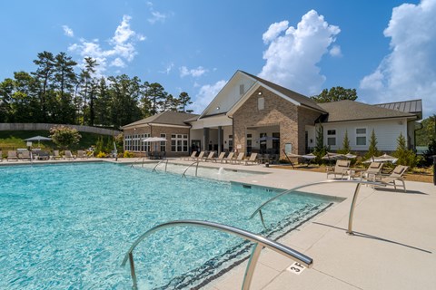 A large swimming pool in front of a building with a sunny sky.