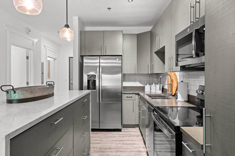 A modern kitchen with a refrigerator, oven, and sink.