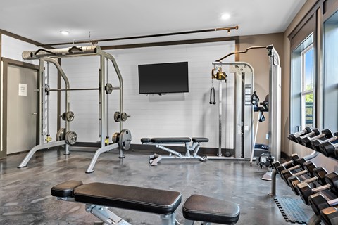 A well-equipped gym with a television mounted on the wall.