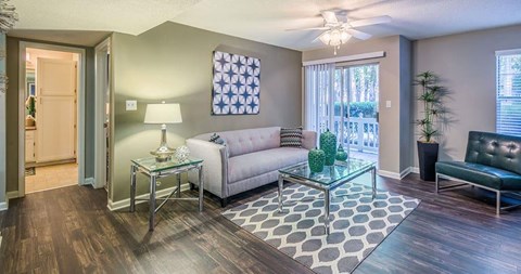 A living room with a glass coffee table and a grey sofa.