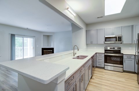 A modern kitchen with a white countertop and stainless steel appliances.