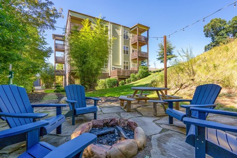 a patio with blue chairs and a fire pit     and a building