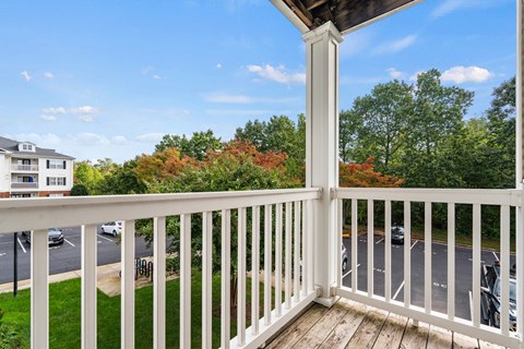 a balcony with a view of a parking lot and trees at SomerHill Farms Apartments, Gainesville, VA