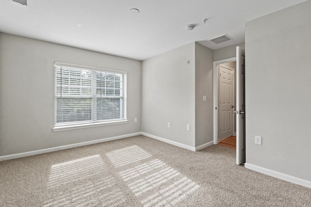 an empty bedroom with a large window and carpet at SomerHill Farms Apartments, Gainesville, VA 20155