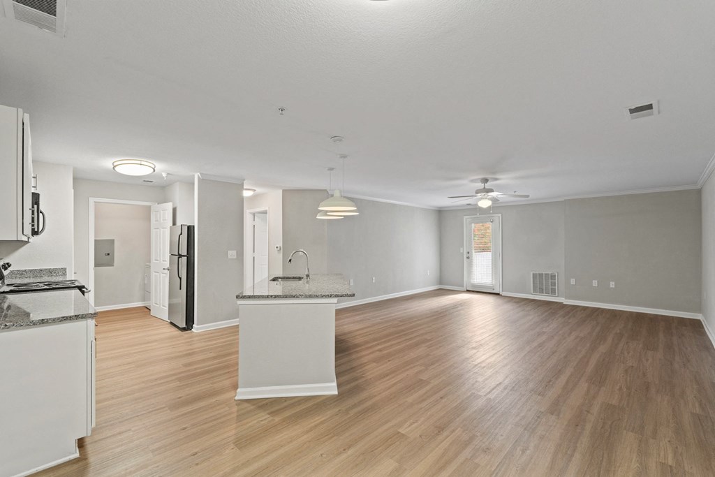 an empty living room and kitchen with wood flooring and white walls at SomerHill Farms Apartments, Gainesville