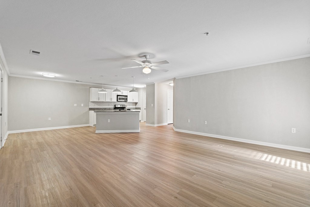 the living room and kitchen of an empty house with wood floors and a ceiling fan at SomerHill Farms Apartments, Virginia , 20155