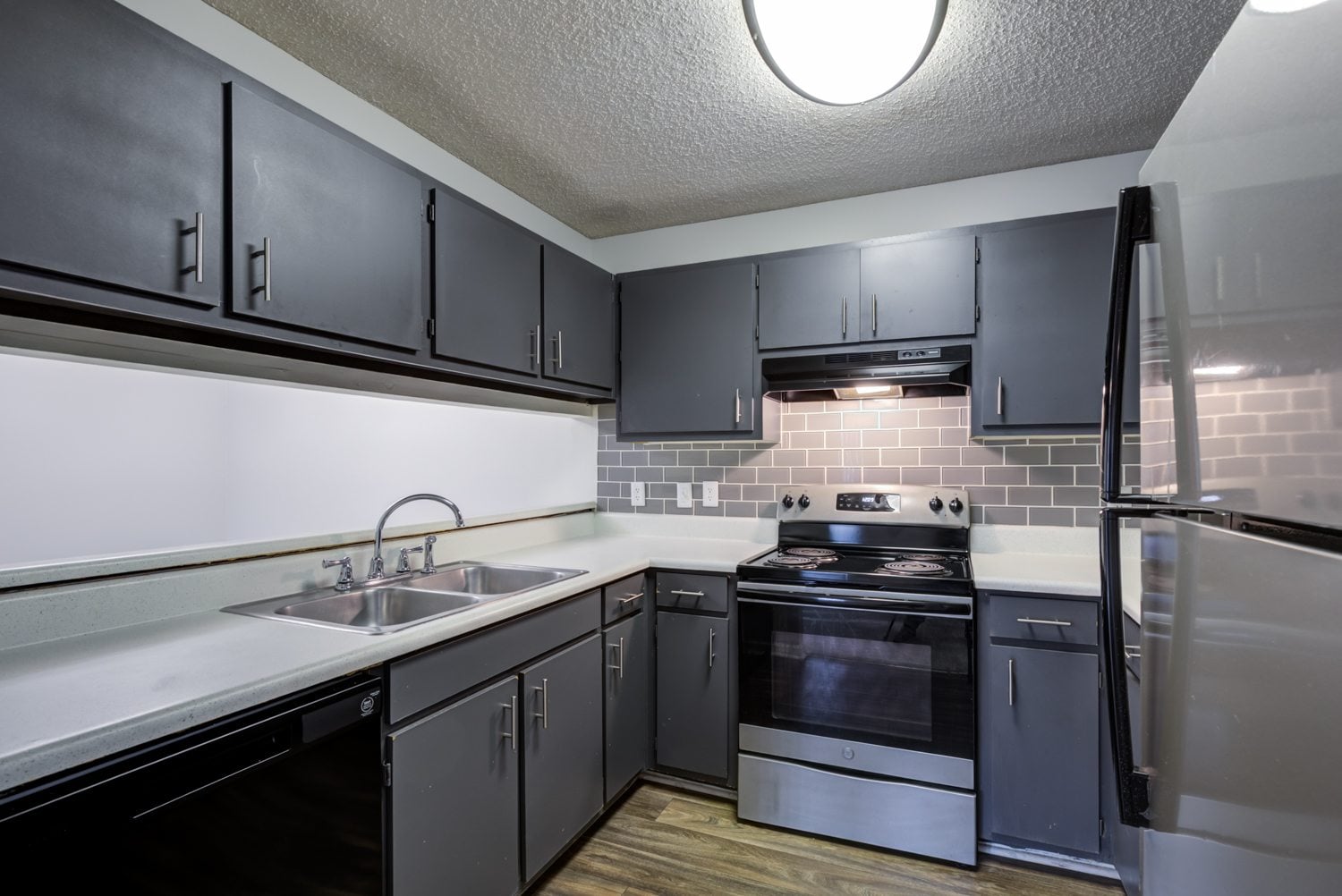 A kitchen with black cabinets and stainless steel appliances.