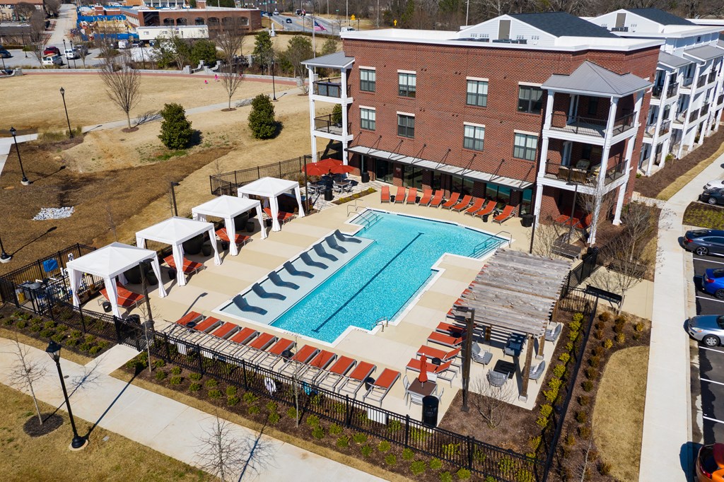 an aerial view of the resort style pool with red lounge chairs and umbrellas at The Flats at Southlawn Apartments, Lawrenceville, 30046