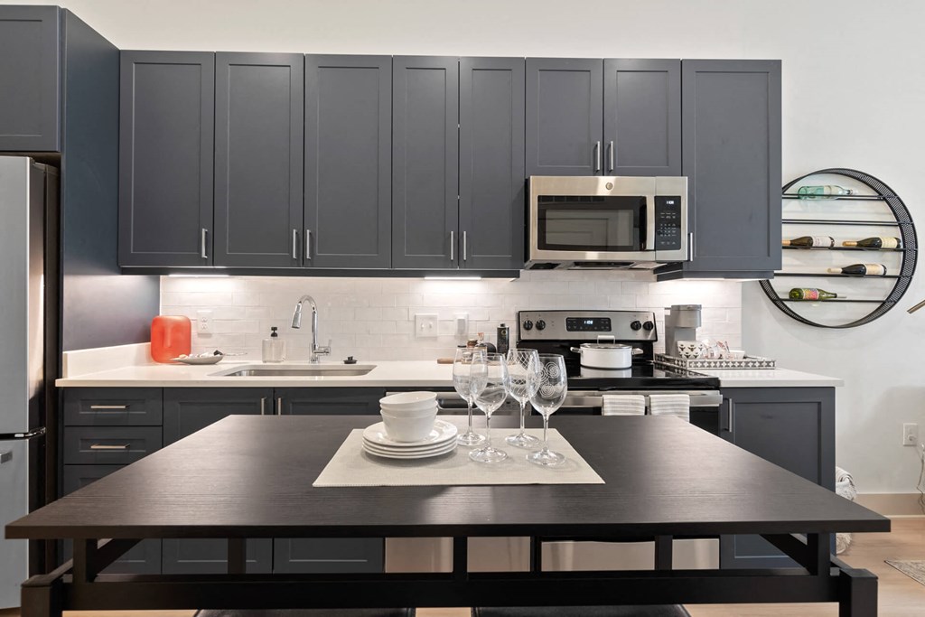 a kitchen with gray cabinets and a black table at Tapestry West, Richmond