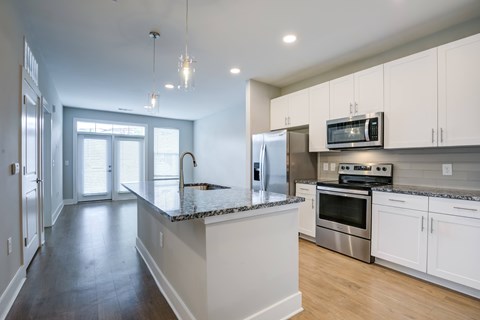 A kitchen with white cabinets and a granite countertop.