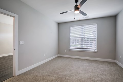 A room with a ceiling fan and a window with blinds.