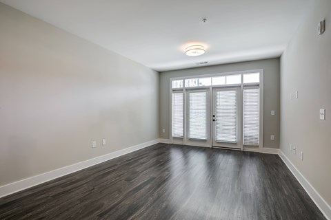 A room with wooden flooring and a window with blinds.