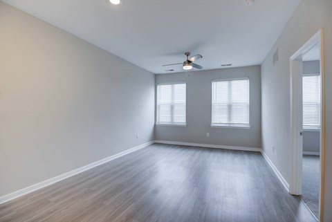 A room with a ceiling fan and two windows.