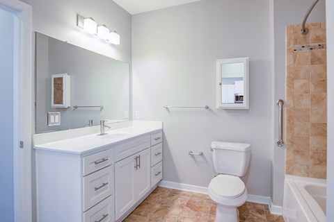 A white bathroom with a toilet, sink, and mirror.