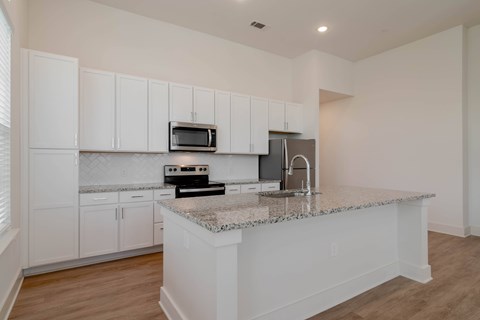 A kitchen with white cabinets and a granite countertop.
