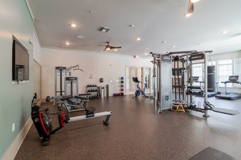 A spacious gym with a variety of equipment including a treadmill, a bench press, and a squat rack.