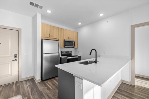 A kitchen with a white counter top and a black faucet.