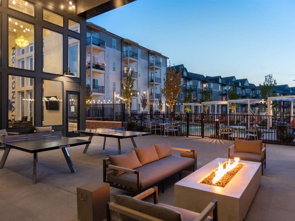a patio with couches and tables and a fire pit in front of an apartment building at Livingston Flats Apartments, Chesterfield, VA, 23832