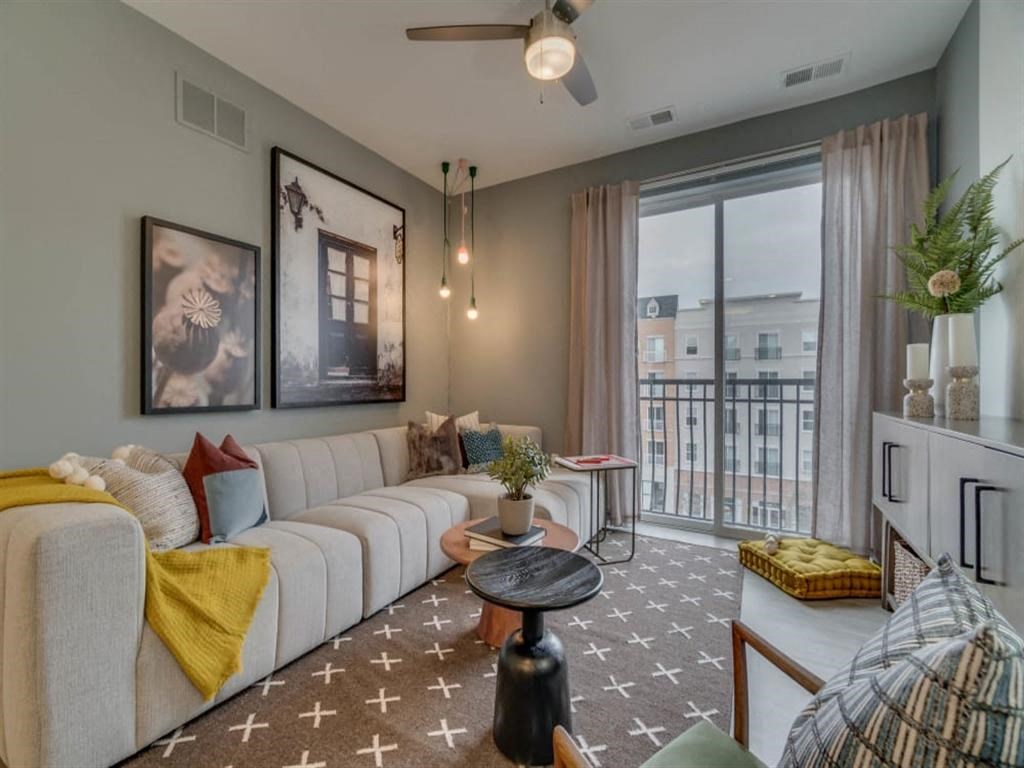 a living room with a white couch and a large window at Flats at West Broad Village, Virginia
