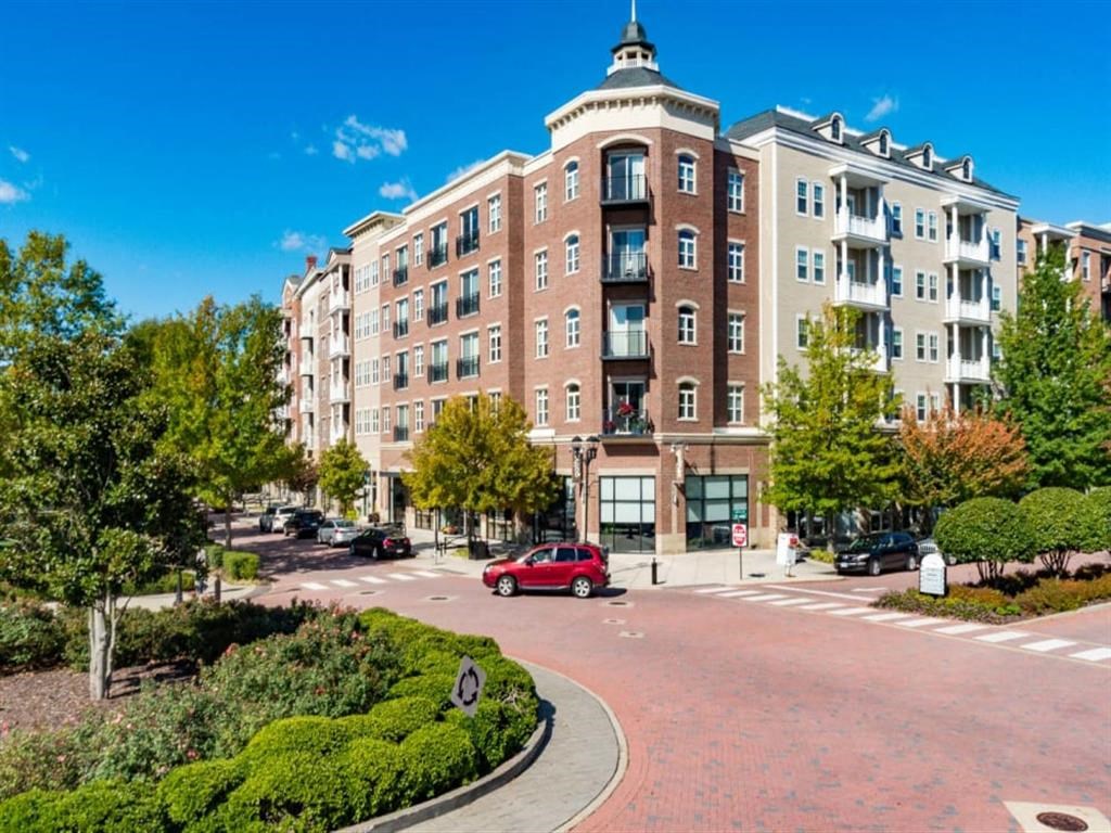 a large apartment building with a red car parked in front of it at Flats at West Broad Village, Virginia