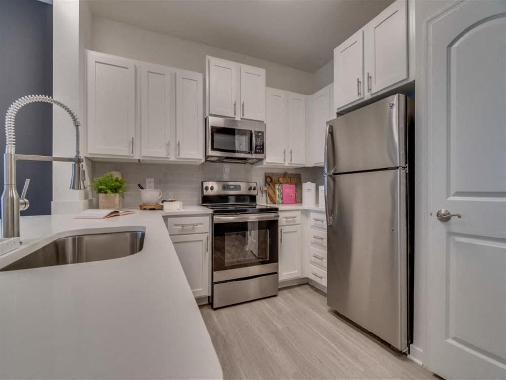 a kitchen with white cabinets and stainless steel appliances at Flats at West Broad Village, Glen Allen, VA