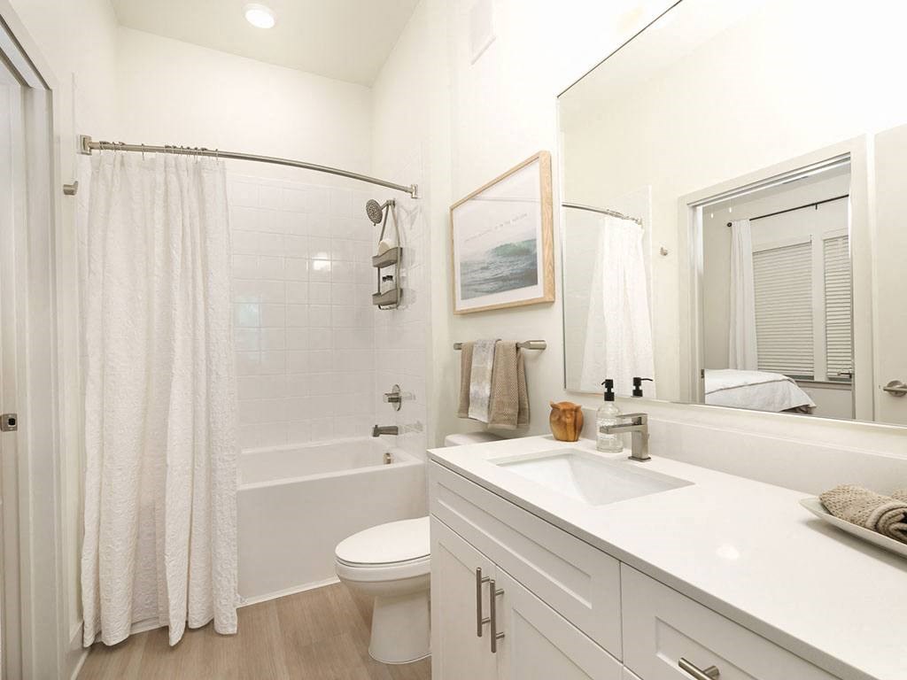 a bathroom with a white sink and toilet next to a white bathtub with a shower curtain at Artistry at Winterfield Apartments, Midlothian, VA