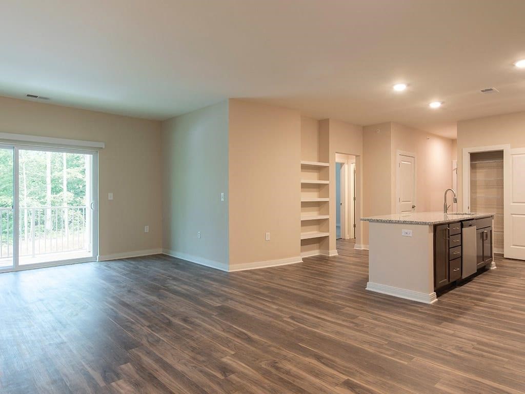 an empty living room with a kitchen and a door leading to a balcony  at Sapphire at Centerpointe, Midlothian, VA
