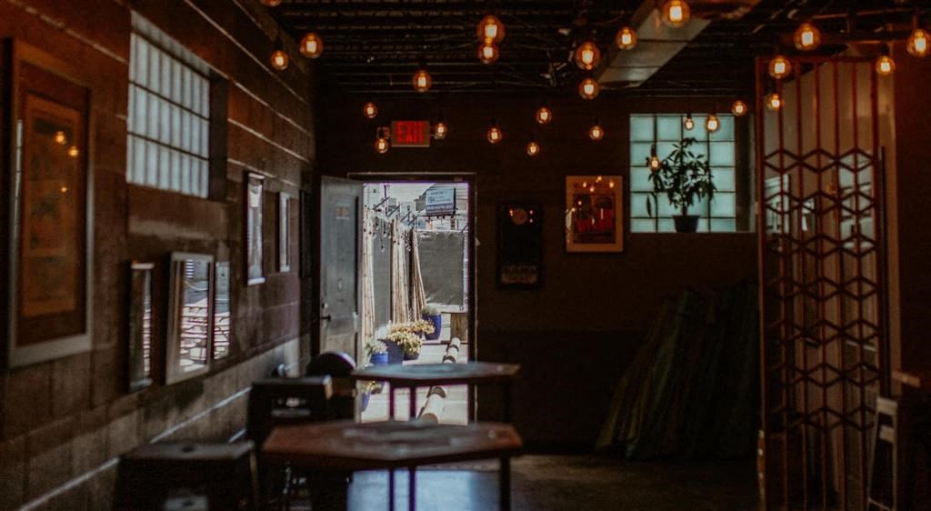 a room with tables and chairs and lights hanging from the ceiling