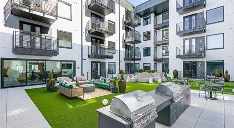 an outdoor living area with barbecue grills and patio furniture in an apartment building