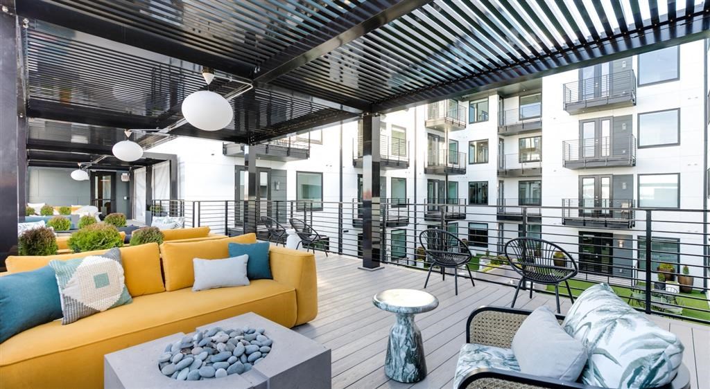 a patio with a yellow couch and a table
