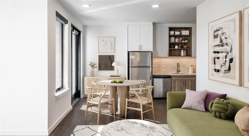 a living area with a round table and chairs and a kitchen in the background