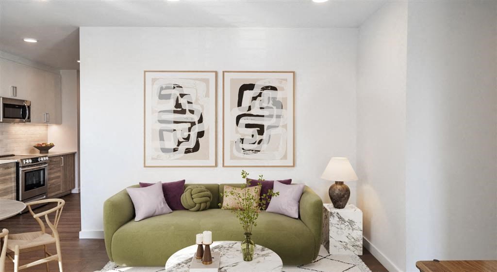 a living room with a green couch and two paintings on the wall