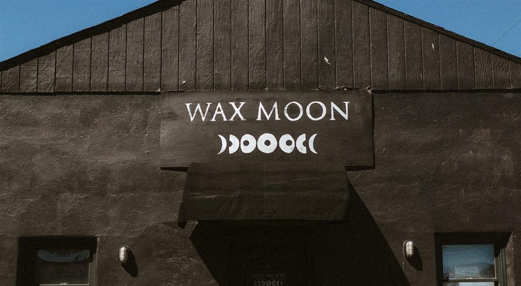 a black building with a sign that reads wax moon