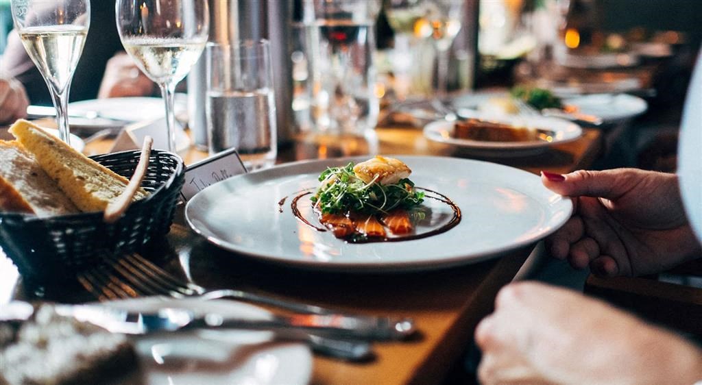 a person holding a plate of food on a table