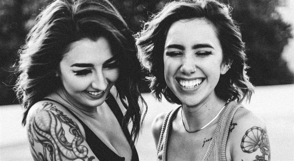 a black and white photo of two women with tattoos