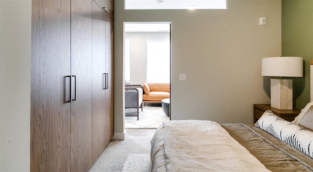 a bedroom with a bed and a door to a living room