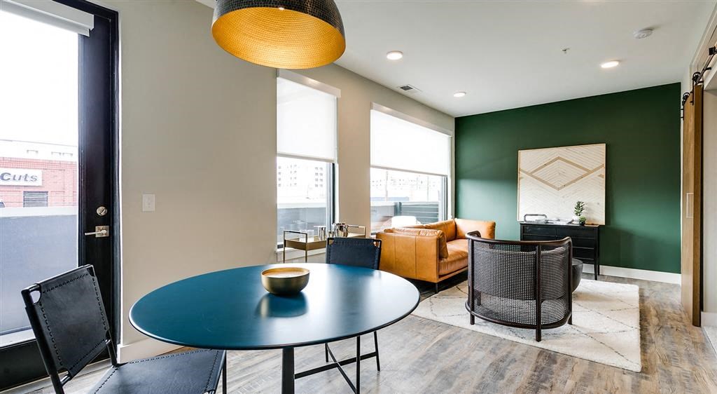 a dining area with a blue table and chairs and a brown couch in the background
