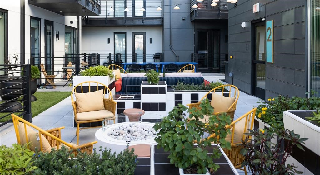 a patio with chairs and a fire pit in front of a building