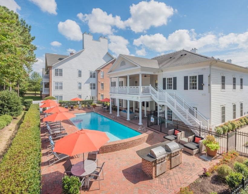 a swimming pool with umbrellas and chairs in front of a house at Sterling Manor, Virginia