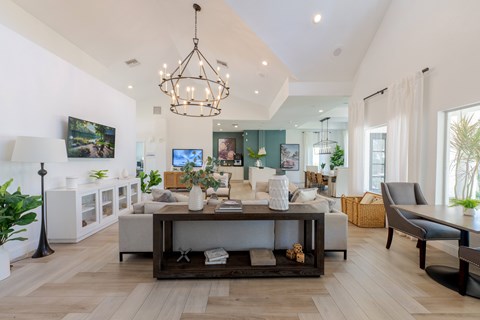 A modern living room with a white sofa set and a chandelier.