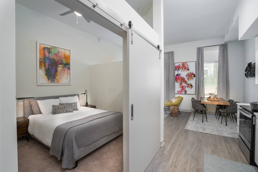 a bedroom with a bed and a living room with a dining room a bedroom with a bed and a living room with a dining room at Vista Brooklynn Apartments, Jacksonville, Florida