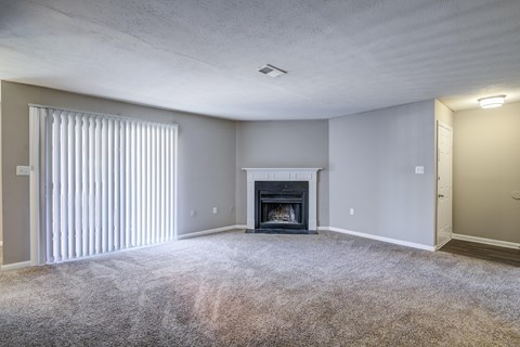 A living room with a fireplace and carpeted floor.