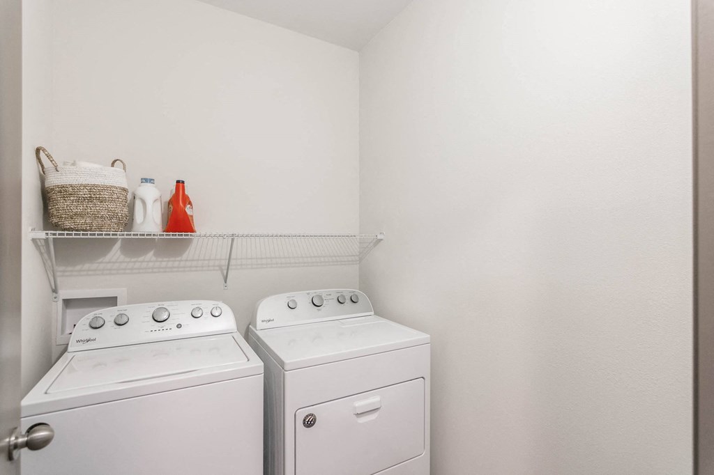 a washer and dryer in a white laundry room with a shelf above them at Village at Westland Cove Apartments, Knoxville, TN