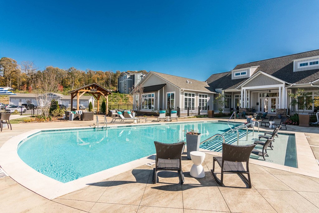 a large swimming pool with chairs and a house in the background a large swimming pool with chairs and a house in the background at Village at Westland Cove Apartments, Knoxville, 37922