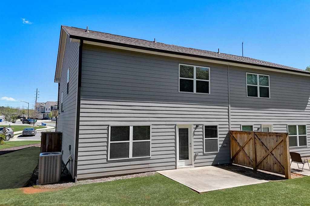 a gray house with a wooden gate and a driveway