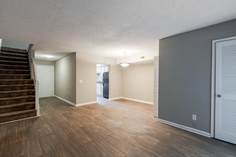 A room with wooden floors and a staircase leading to another room.