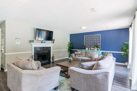 A living room with a fireplace and two grey chairs.