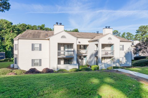 A large, two-story house with a white exterior and a balcony on the second floor.