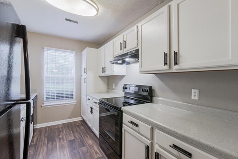 A kitchen with white cabinets and a black fridge.