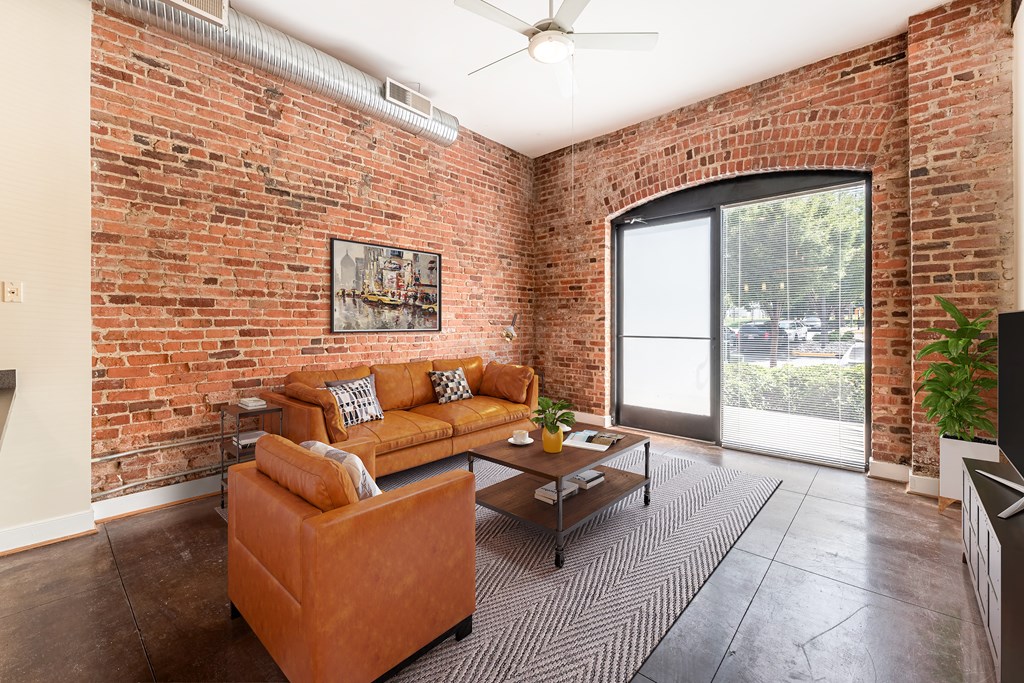 a living room with a couch and a coffee table in front of a brick wall at Mayton Transfer Lofts in Petersburg, Virginia